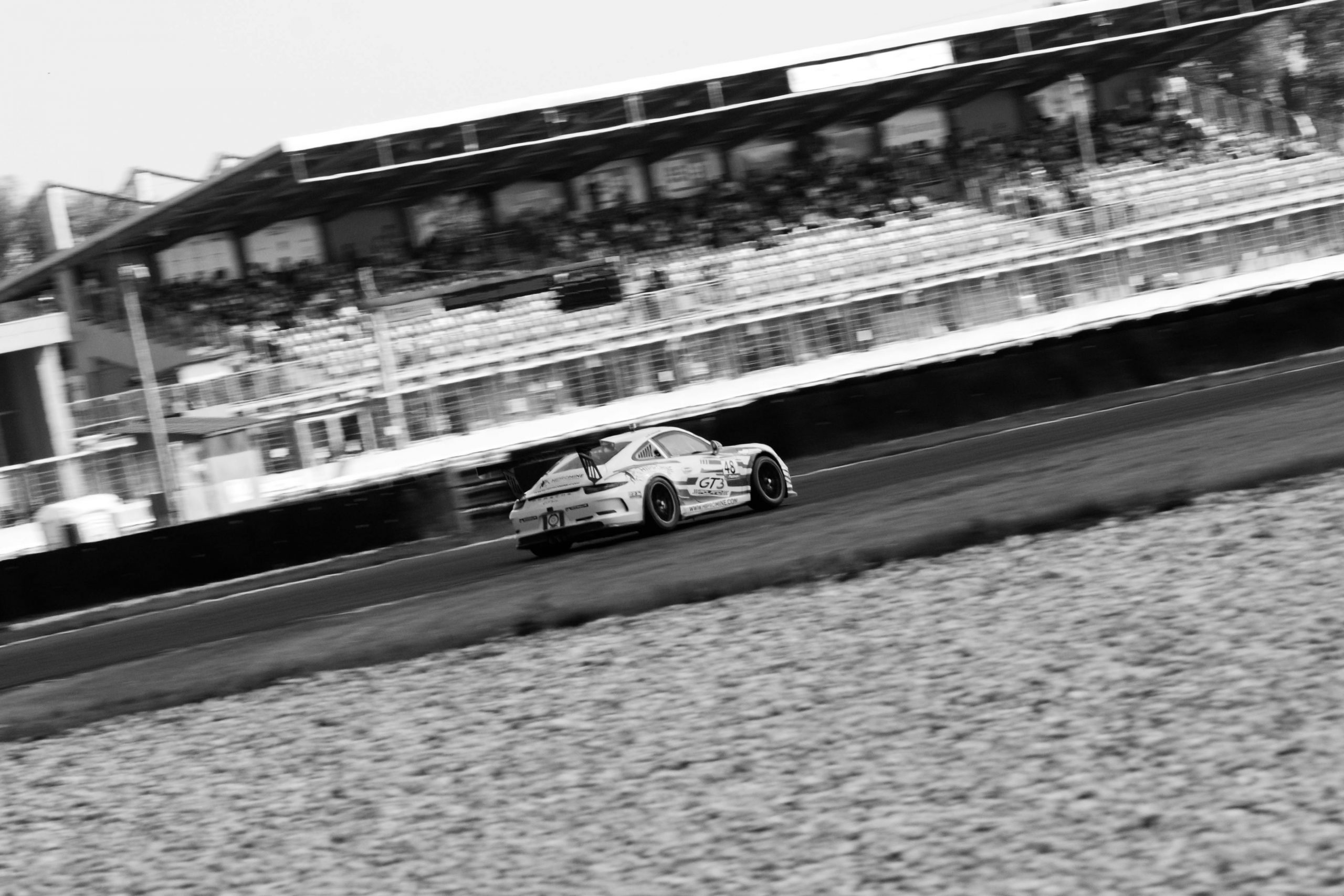 Black and white photo of a race car driver intensely focused, wearing a helmet.